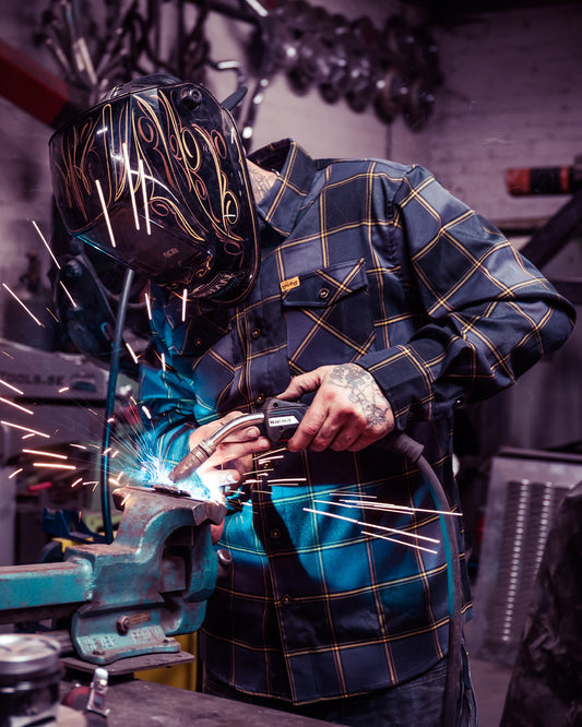 el lobo gray and orange flannel on a welder laying down dimes - main image