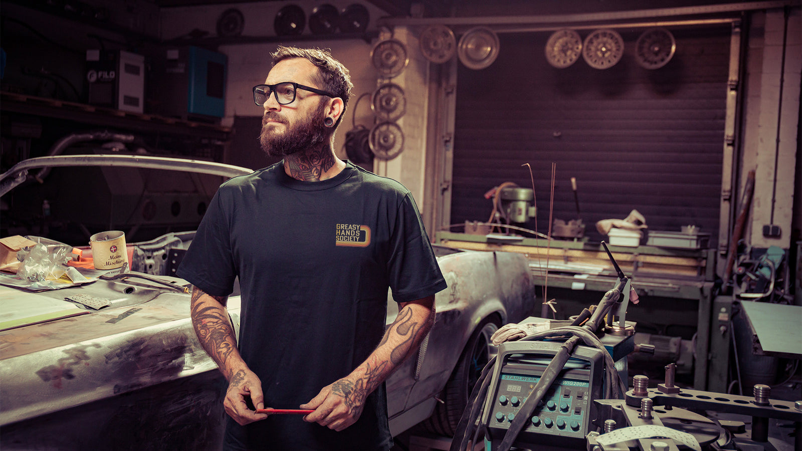 g70 black graphic t-shirt with a retro 70's design being worn by a guy working on his car