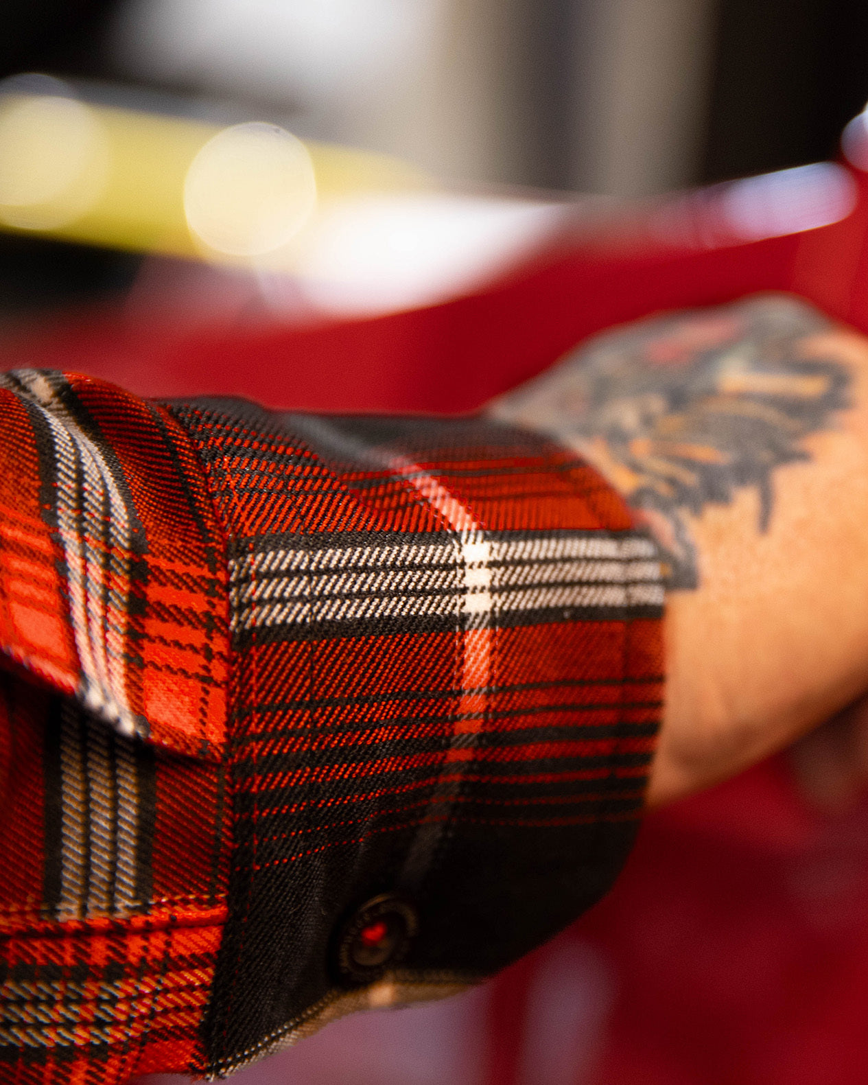 Close-up of a person wearing a red plaid shirt with a blurred background - The Detour Flannel by Greasy Hands Society