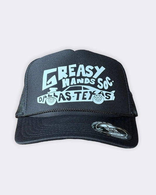 A black trucker hat with a white graphic print reading 'GREASY HANDS SOX' and 'DALLAS TEXAS' with a car illustration, shown against a light gray background - Dallas Dragster Black/White Hat by Greasy Hands Society