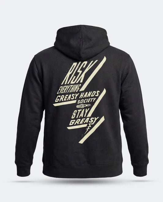 A black pullover hoodie shown from the back, featuring a large cream-colored graphic print with the text 'RISK EVERYTHING - GREASY HANDS SOCIETY - STAY GREASY' and diagonal lightning-bolt shapes, on a light gray background - Bolted Down Black Hoodie by Greasy Hands Society