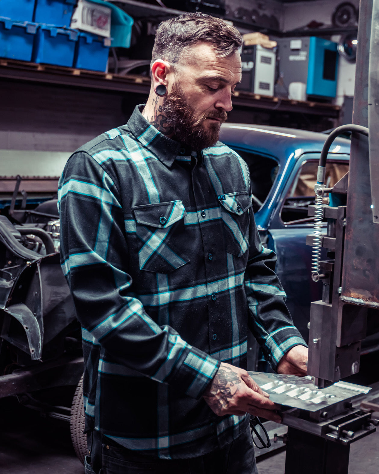 gravity fed blue black and gray flannel on a man doing metal work for his classic hotrod