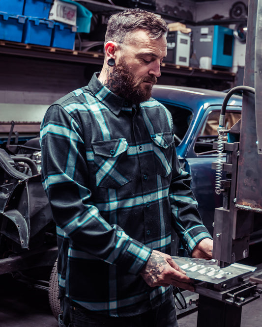 gravity fed blue black and gray flannel on a man doing metal work for his classic hotrod
