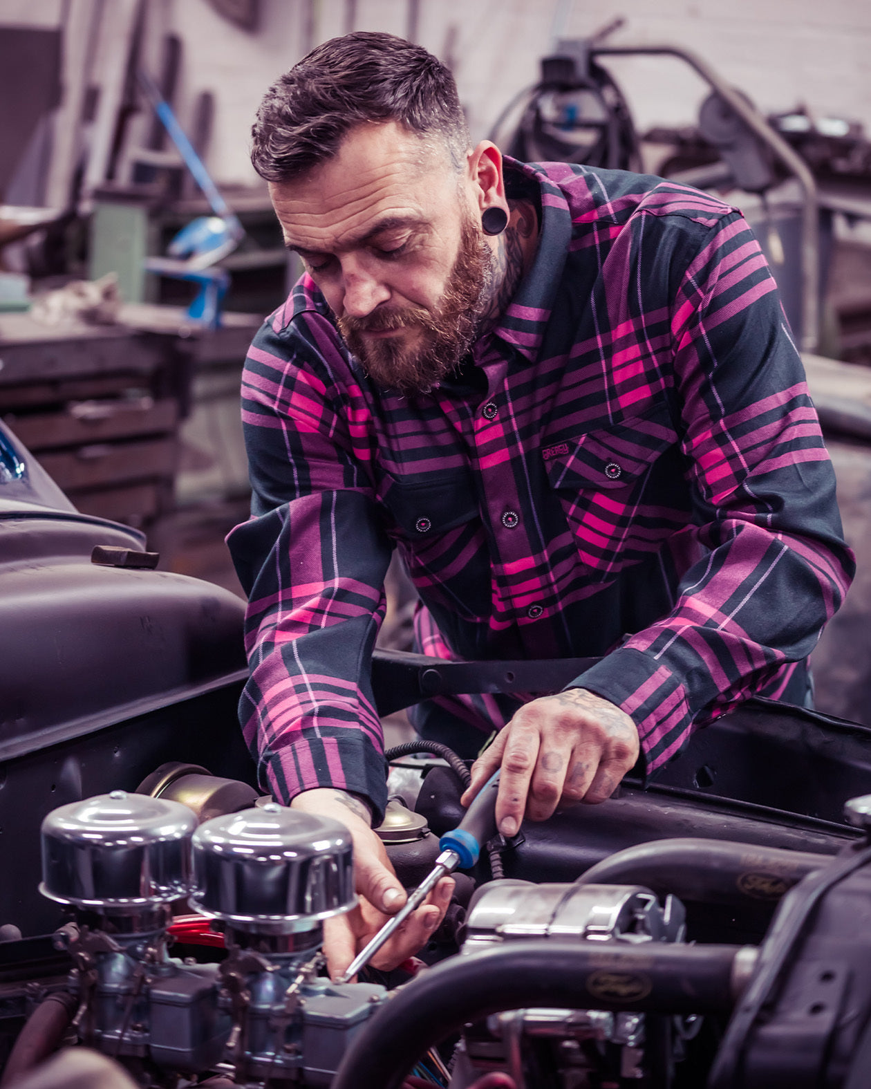 Lonely Heart Flannel black and pink flannel on a model working on the engine of his classic car