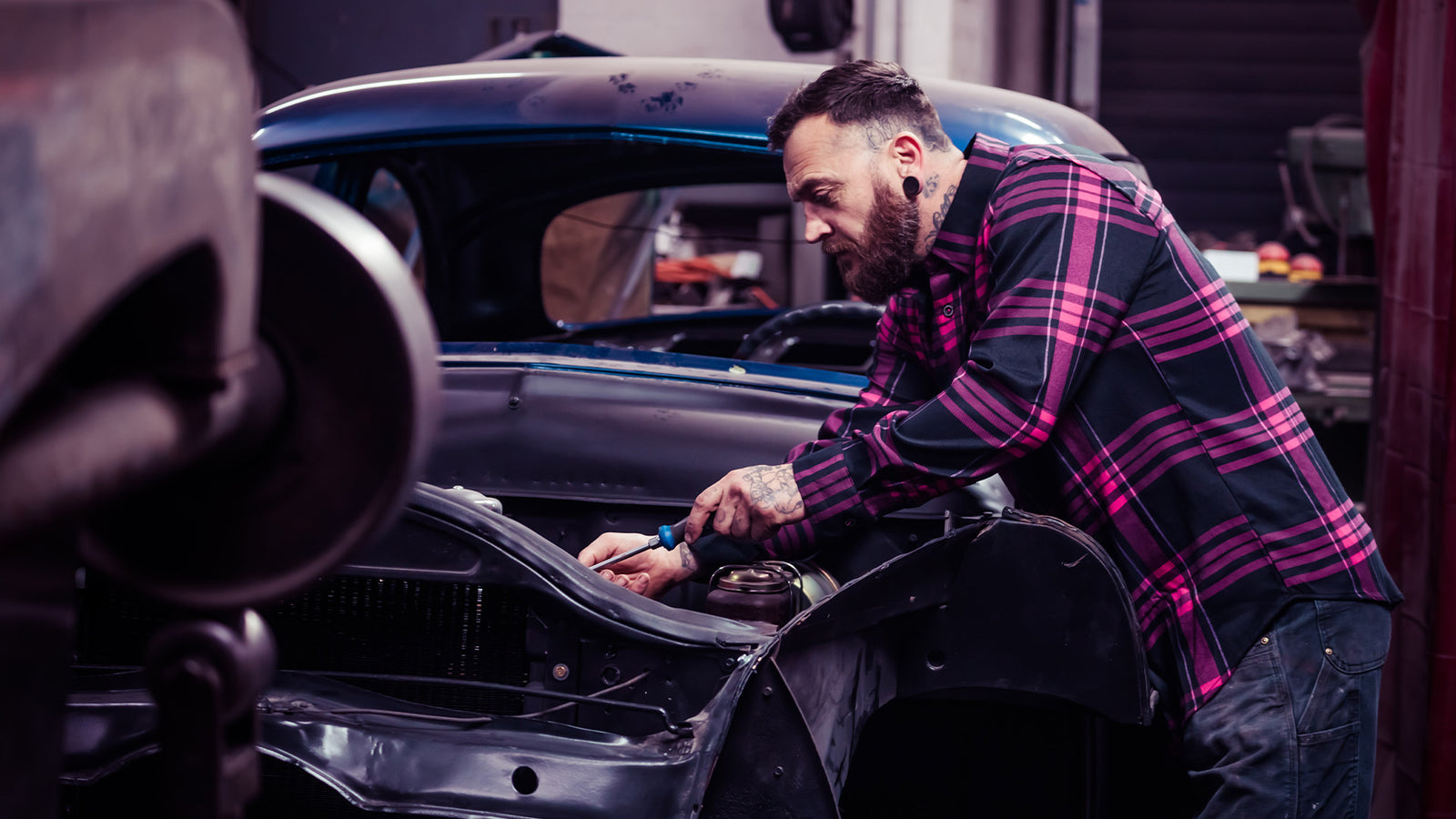 the lonely heart pink and black flannel being worn while working on a classic car