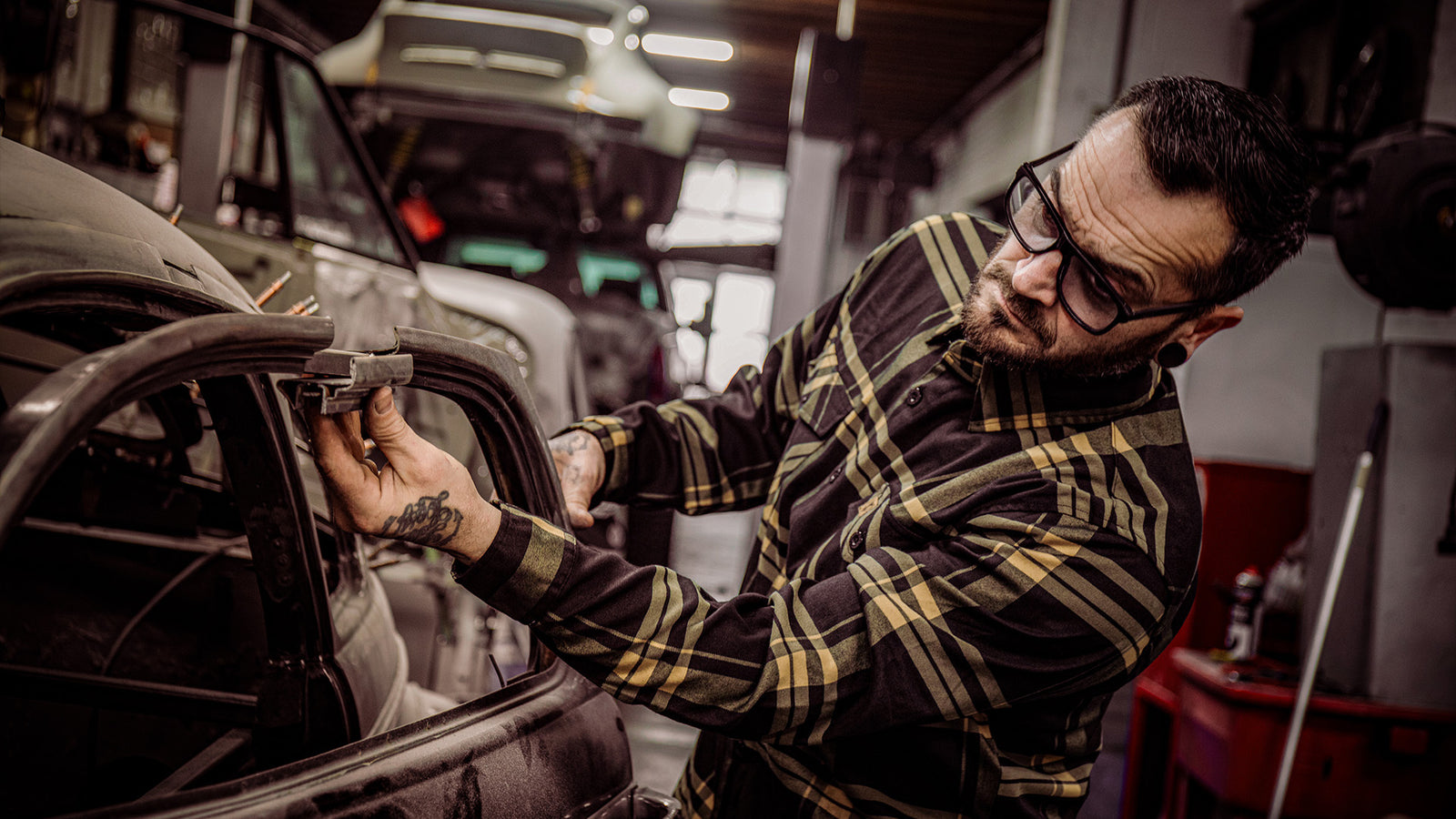 two lane black nd gold flannel being worn by a guy working on his classic car