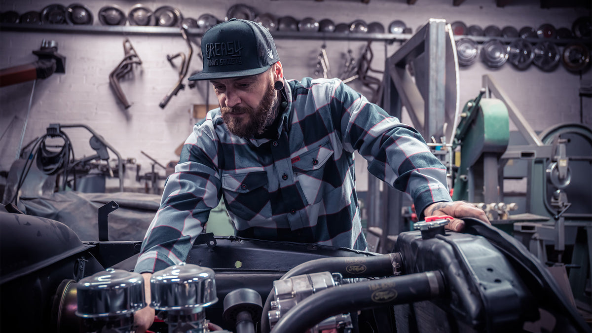 banger flannel being worn while a man works with his hands on an engine