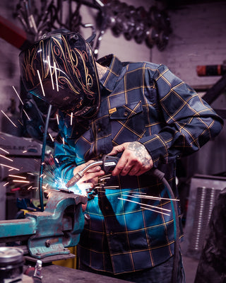 el lobo gray and orange flannel on a welder laying down dimes - main image