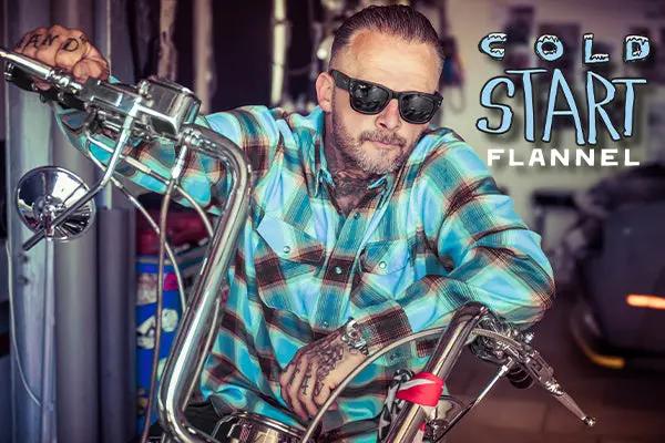 man wearing sunglasses wearing a blue, brown and white flannel shirt while riding a motorcycle with the promotional text "Cold Start Flannel"  - Cold Start Flannel by Greasy Hands Society