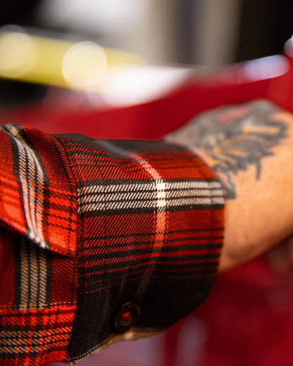 Close-up of a person wearing a red plaid shirt with a blurred background