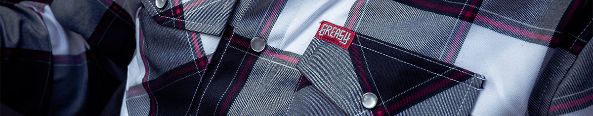 Close-up of a plaid button-up flannel shirt with gray, white, and dark red stripes, featuring a chest pocket with a red and black 'Greasy' label - The Suicide Machine Flannel by Greasy Hands Society