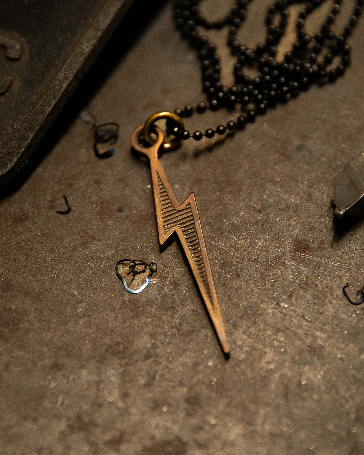 Bronze lightning bolt pendant on a dark surface