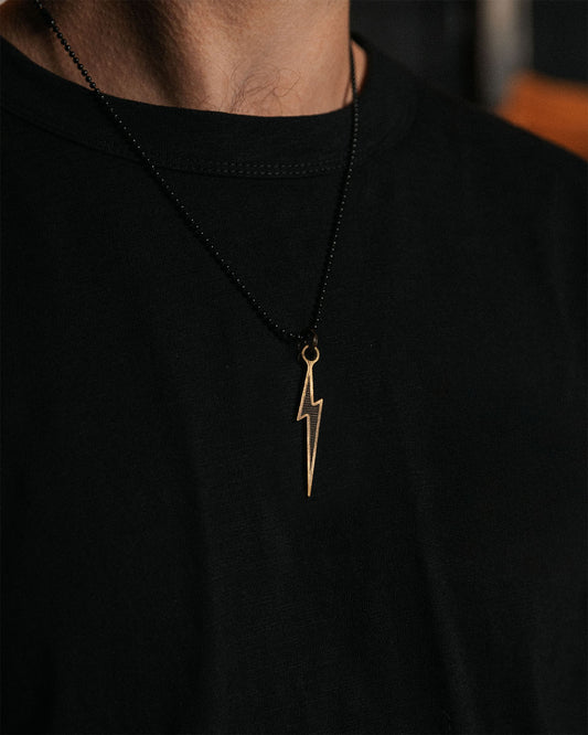 Person wearing a black shirt with a gold lightning bolt necklace.