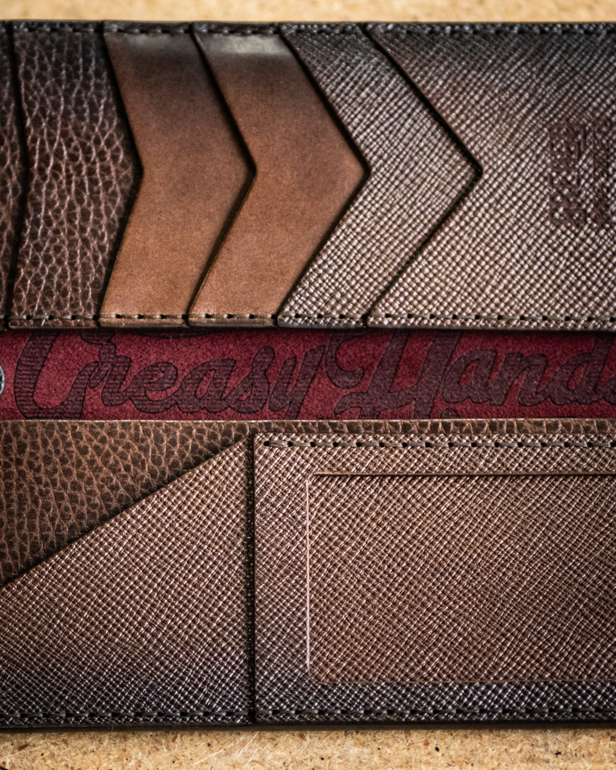 Close-up interior look of a brown leather wallet with 'Greasy Hands Society' branding.