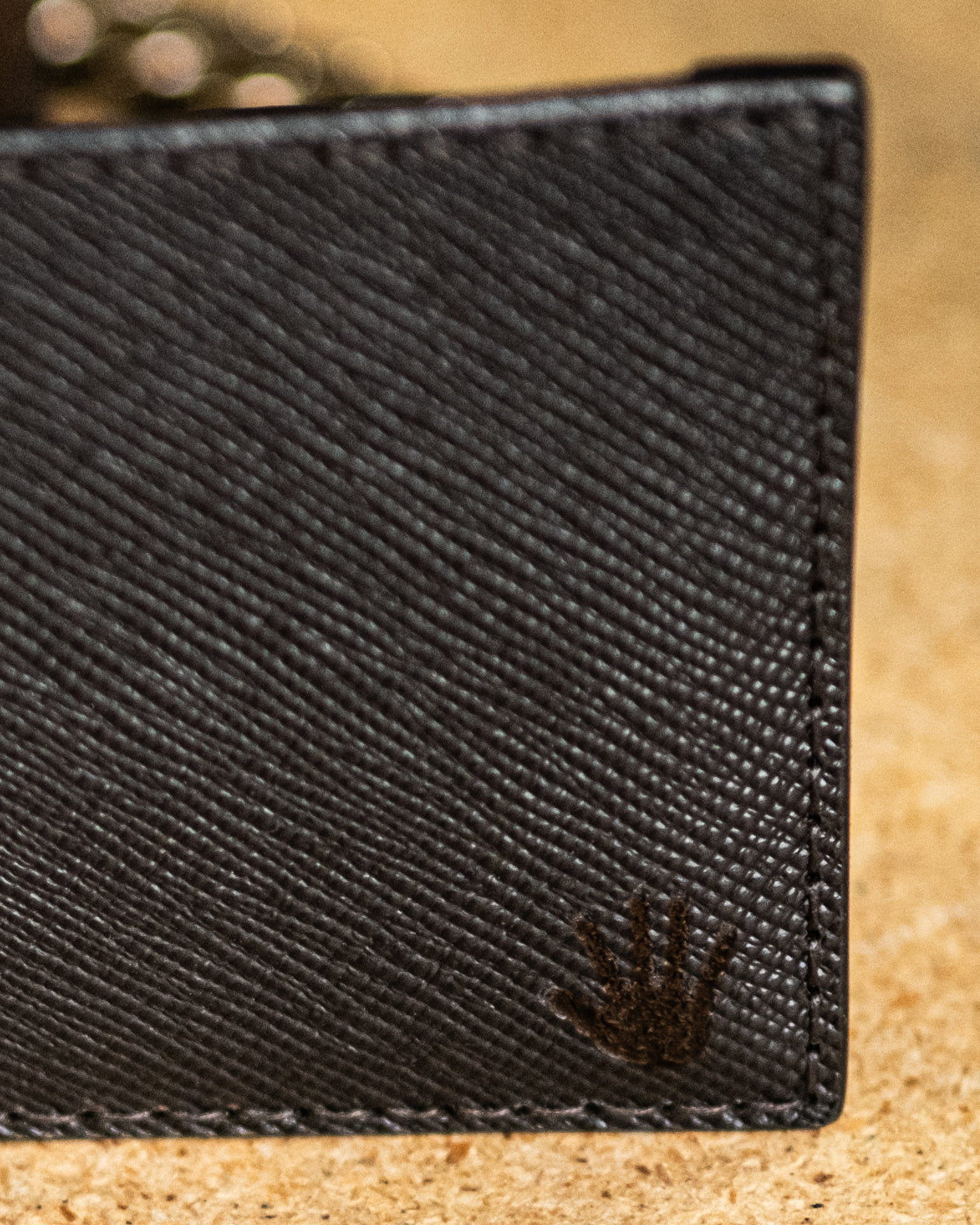 Close-up of a BROWN textured wallet with a brand logo on a beige surface - Horizontal Brown Leather Wallet by Greasy Hands Society
