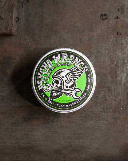 clay-based Pomade container with 'Psycho Wrench' branding on a textured surface