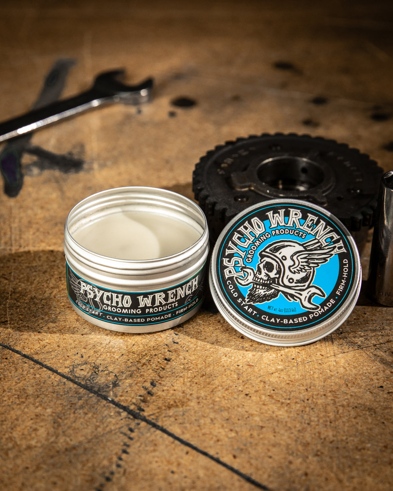 Jar of Psycho Wrench grooming product on a textured surface with tools in the background