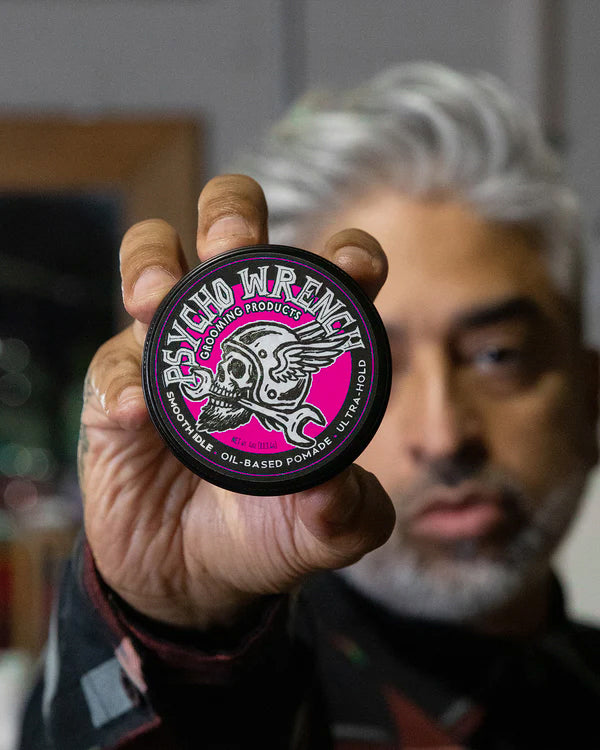 Person holding a container of Psycho Wrench grooming product with smooth idle scent - Psycho Wrench Smooth Idle Pomade by Greasy Hands Society