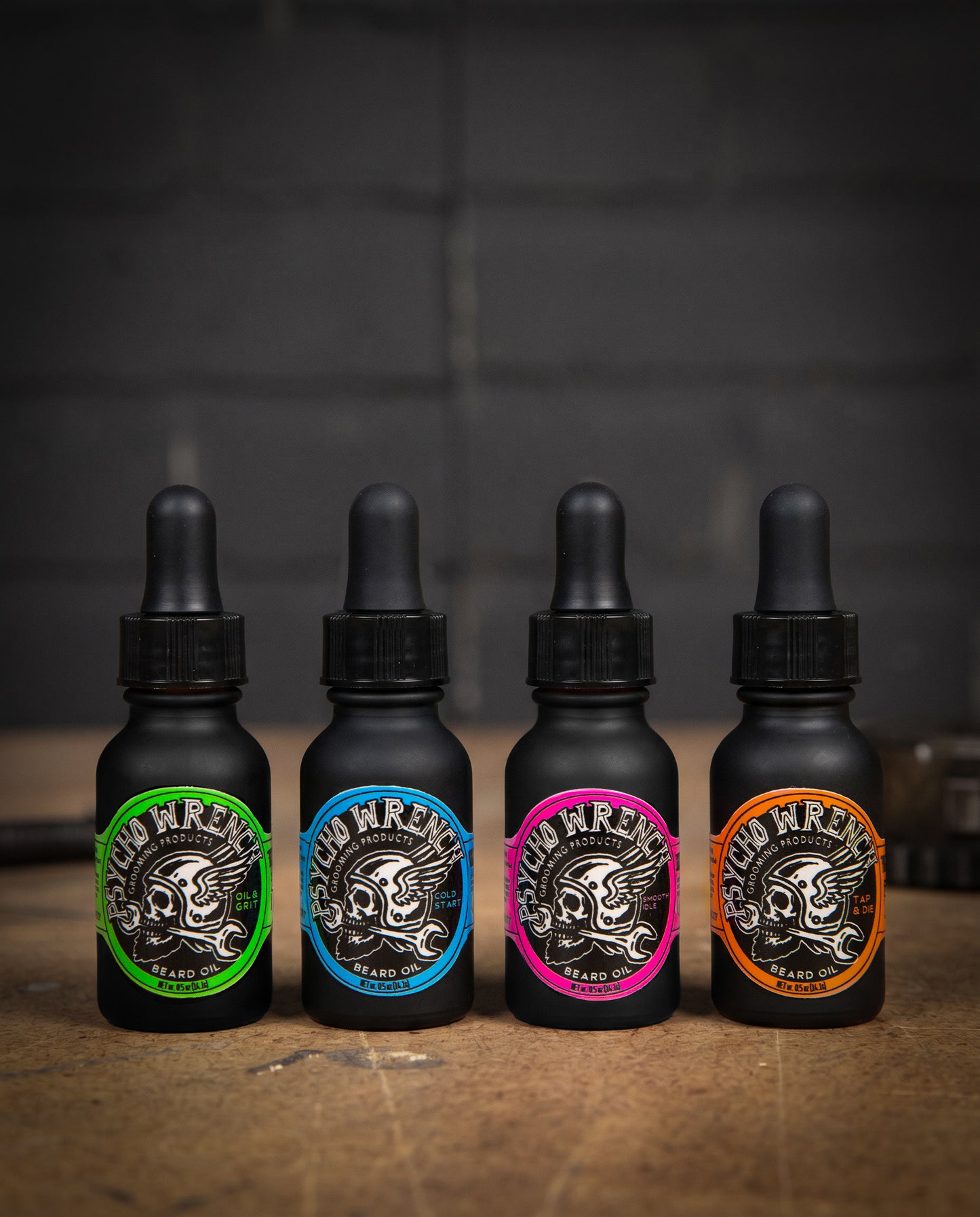 Four black bottles with colorful labels on a wooden surface and dark background - Beard Oil Variety 4-pack by Greasy Hands Society