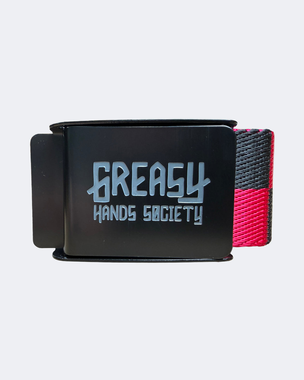 A black belt buckle featuring the 'Greasy Hands Society' logo in a stylized silver font, with a woven strap showing black and pink sections, set against a light gray background -Pink Noise Belt by Greasy Hands Society