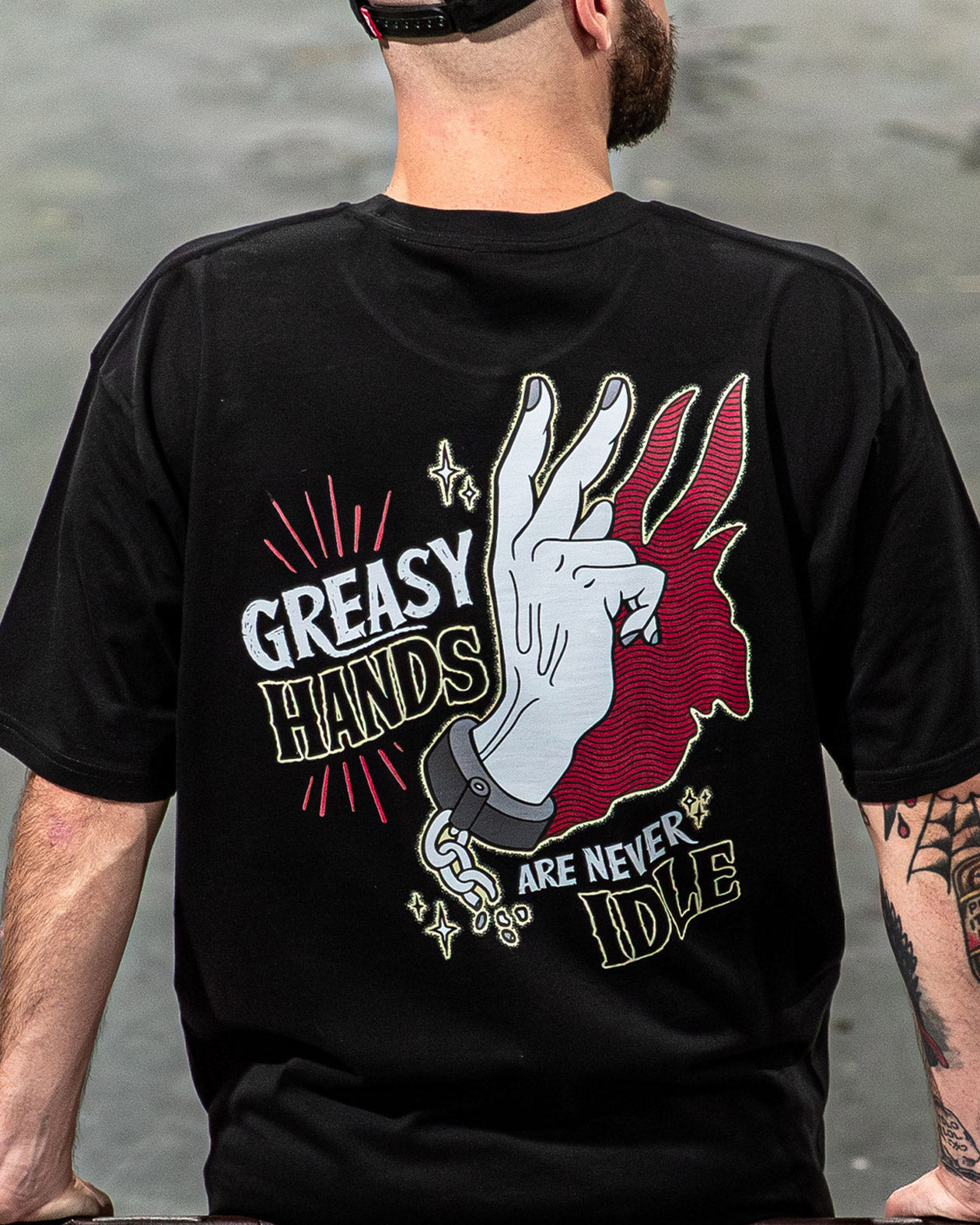 never idle black graphic tee back showing chained hands and the words "Greasy Hands are never idle"