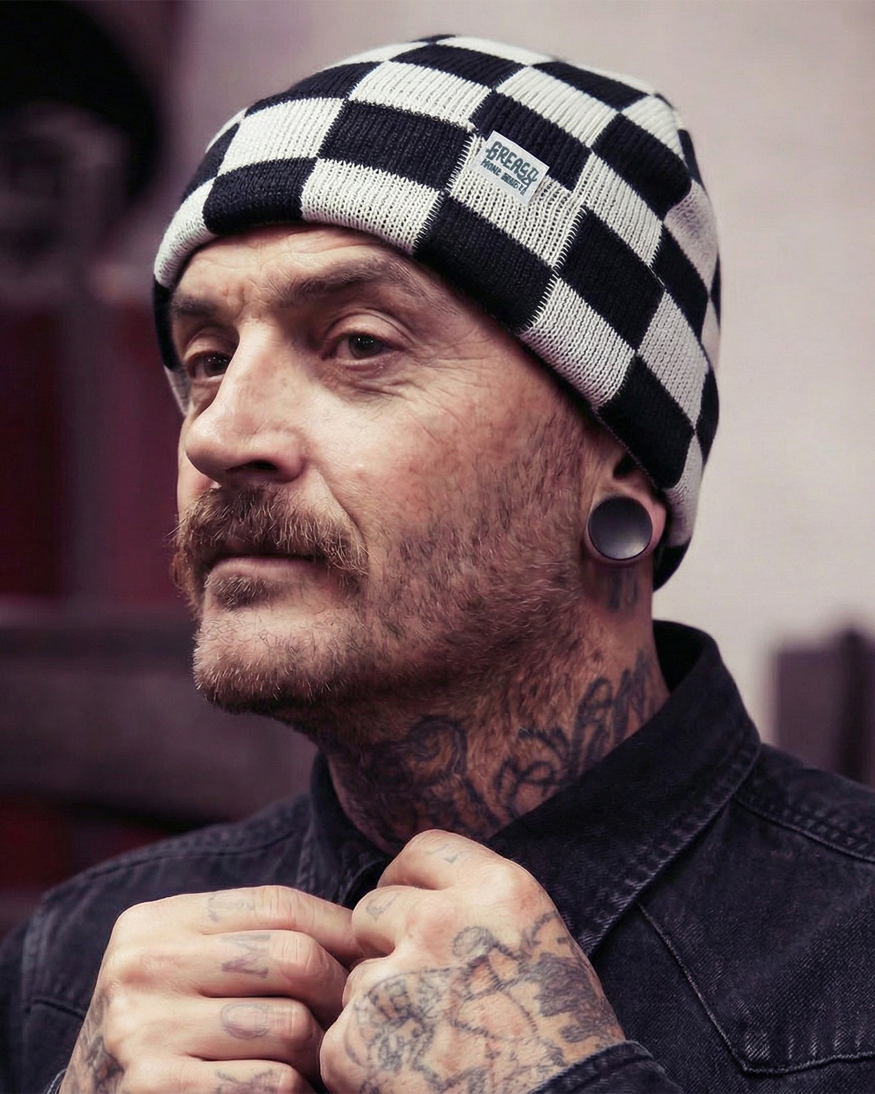Man wearing a checkered beanie with tattoos on his face and neck - Finish Live checkered beanie by Greasy Hands Society