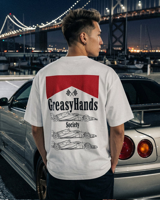 Person wearing a 'Greasy Hands Society' boxy streetwear JDM t-shirt with a bridge and boats in the background