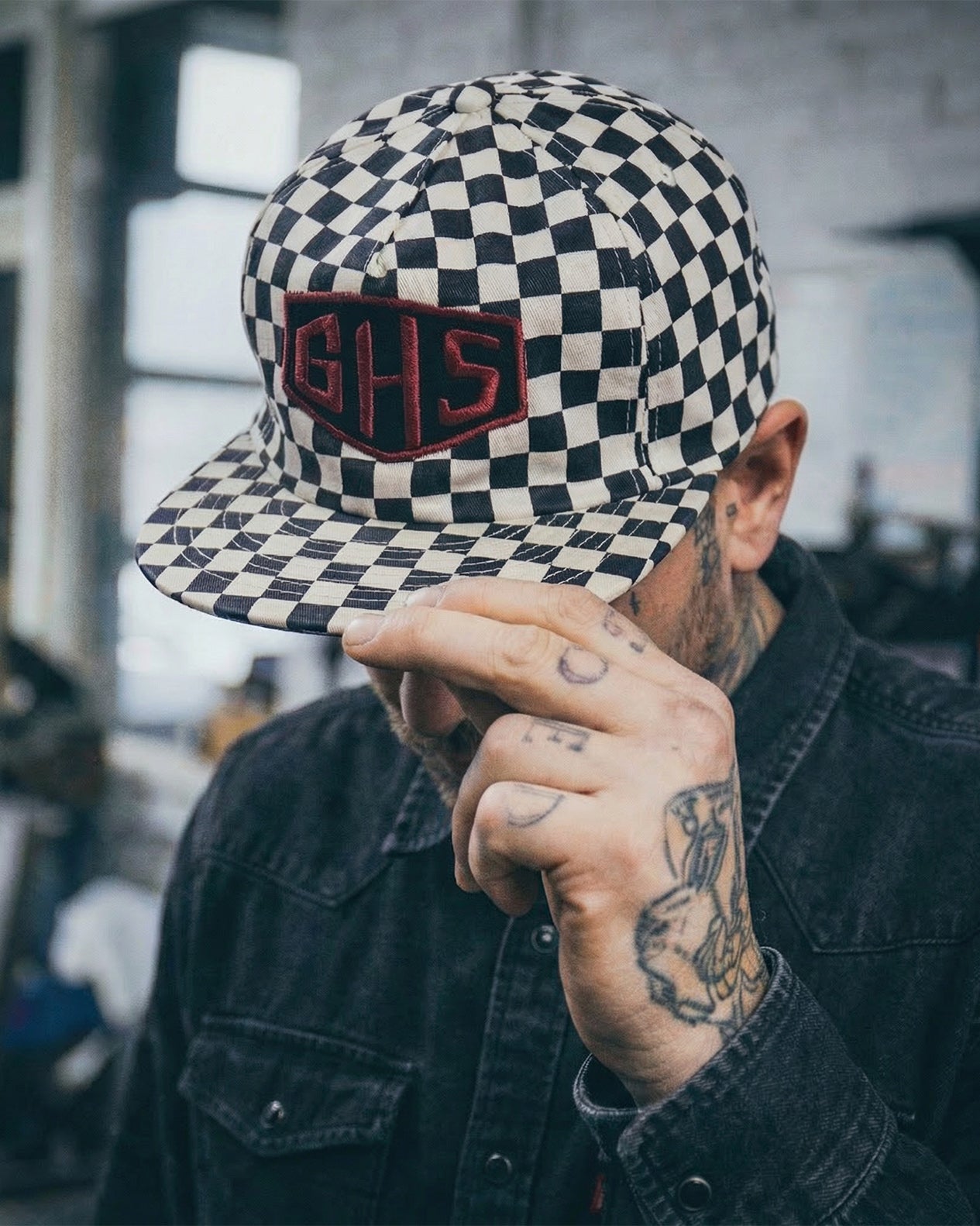 Person wearing a checkered cap with a logo, indoors.