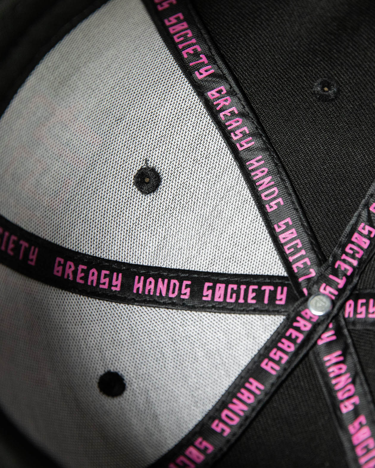 interior of a Black cap with pink text on a dark background