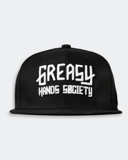 Black cap with white 'Greasy Hands Society' logo on a light gray background