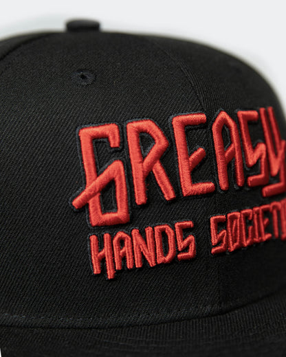 detail shot of a black cap with red greasy hands society logo on the front - showing the stitching