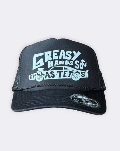A black trucker hat with a white graphic print reading 'GREASY HANDS SOX' and 'DALLAS TEXAS' with a car illustration, shown against a light gray background - Dallas Dragster Black/White Hat by Greasy Hands Society