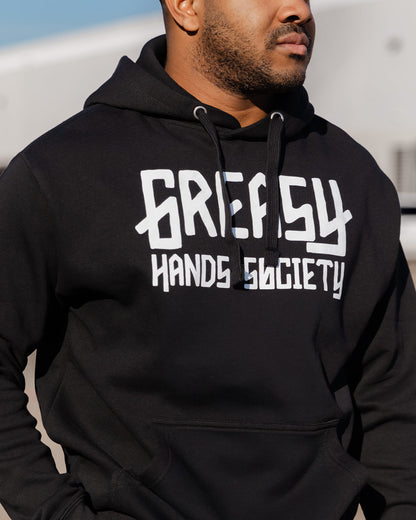 Person wearing a black hoodie with 'Greasy Hands Society' logo - GHS Logo Hoodie by Greasy Hands Society