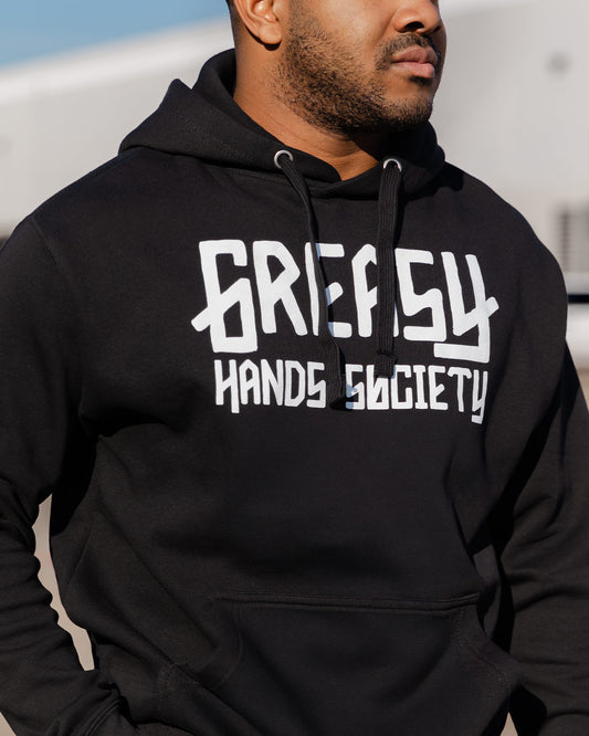 Person wearing a black hoodie with 'Greasy Hands Society' logo - GHS Logo Hoodie by Greasy Hands Society