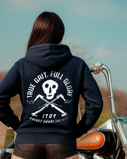 woman wearing a black hoodie that says true grit full glory with a skull design on a motorcycle