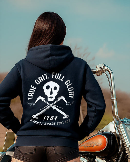 woman wearing a black hoodie that says true grit full glory with a skull design on a motorcycle