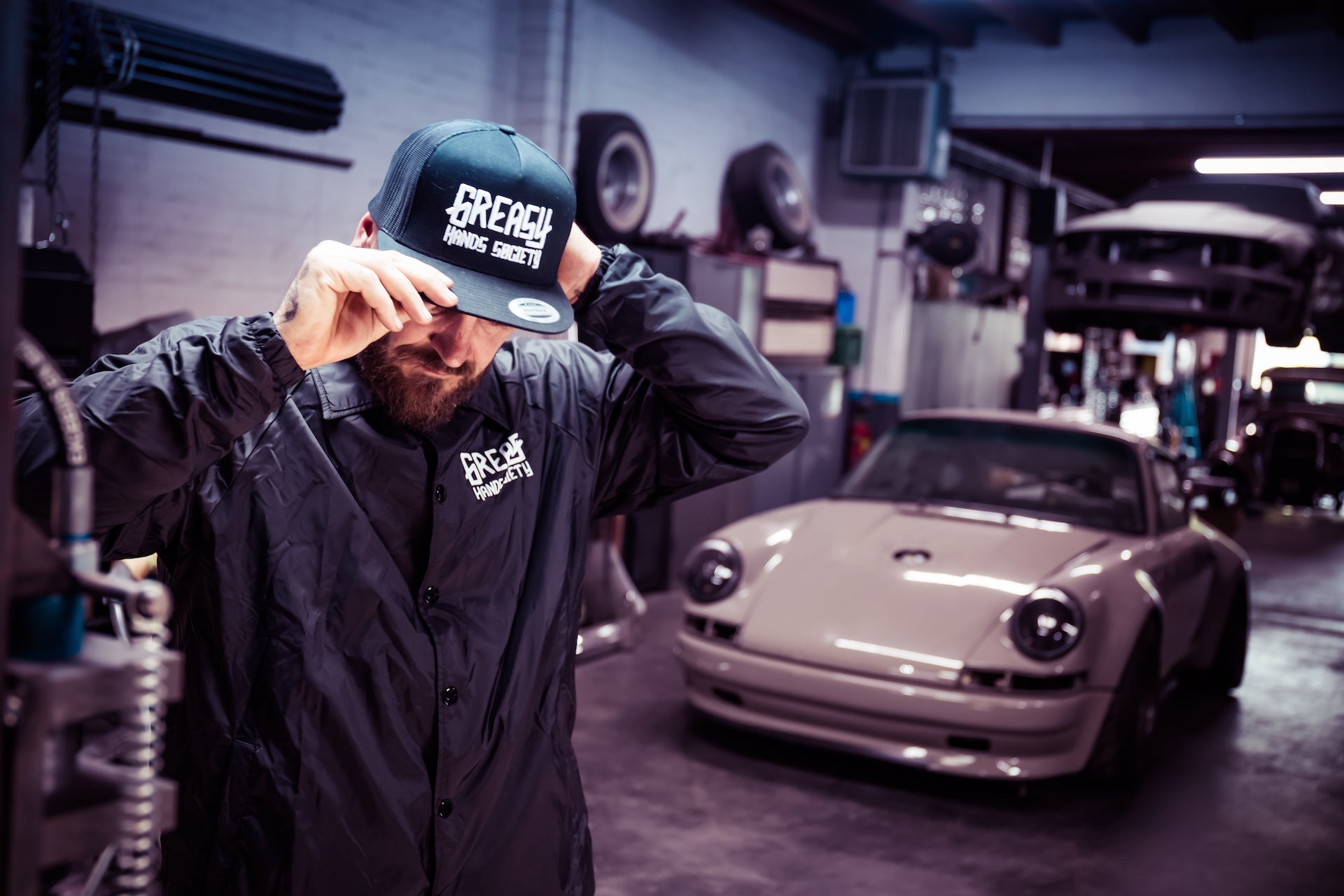 Person wearing a cap with 'French Racing' branding in a garage with a car in the background