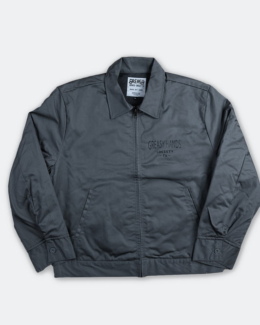 steel gray mechanic jacket with greasy hands society TX - text on the front left chest  n a white background