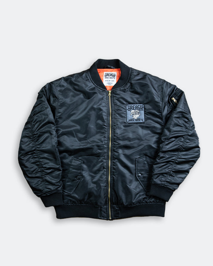 Black bomber jacket with patches on a light gray background