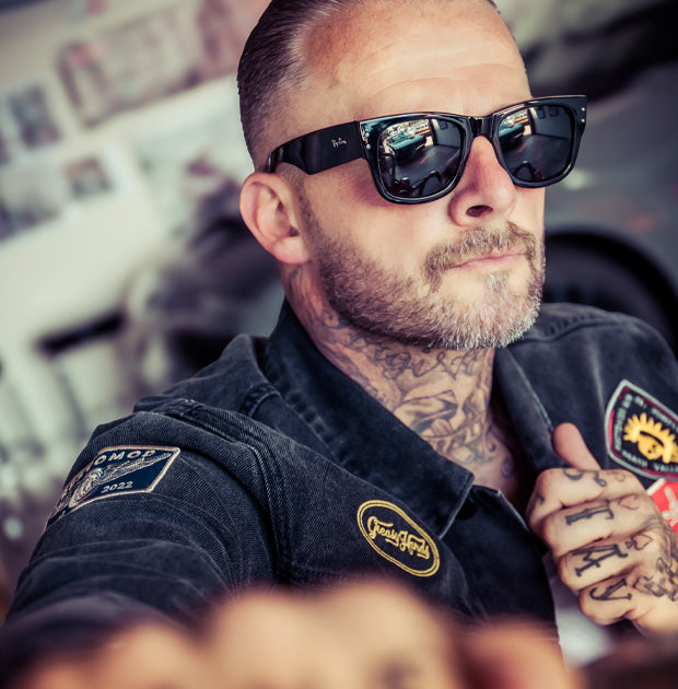 man with tattoos wearing sunglasses in a industrial warehouse - The Black Denim Jacket by Greasy Hands Society