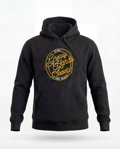 A black pullover hoodie with a large circular gold graphic on the chest reading 'Greasy Hands Society' and smaller text 'EST. 2016' and 'SAN DIEGO, CA', shown on a clean white background - Self Made Hoodie by Greasy Hands Society