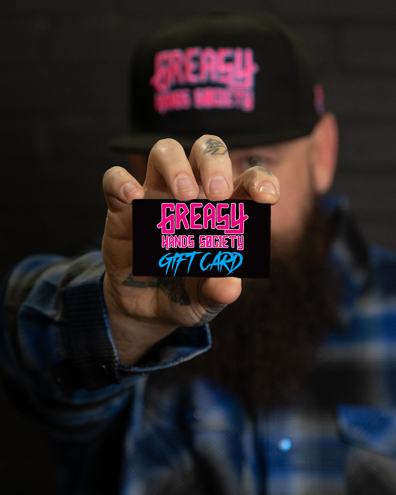 Person holding a 'Greasy Hands Society Gift Card' with a dark background