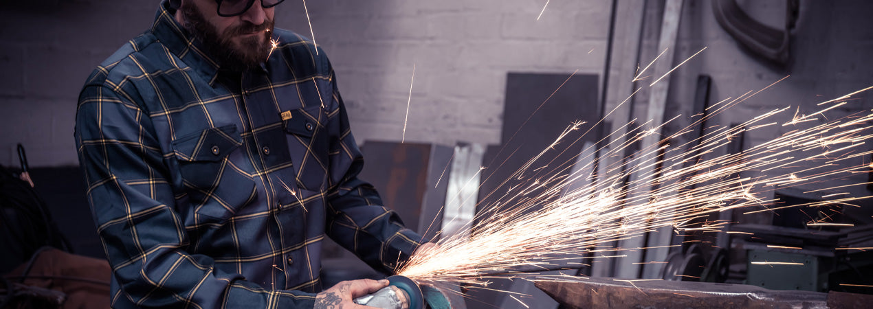 Person welding with sparks flying in a workshop setting - El Lobo Flannel by Greasy Hands Society