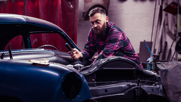 Man wearing a black and pink plaid shirt working on a car in a garage - Lonely Heart Flannel by Greasy Hands Society