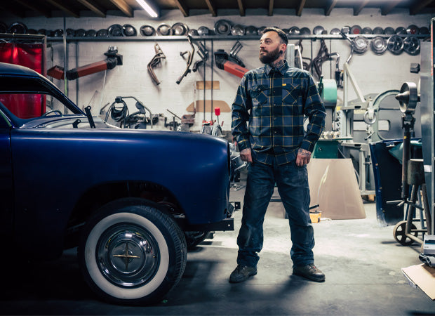 Man standing in a garage with tools and a vintage car - El Lobo Flannel by Greasy Hands Society