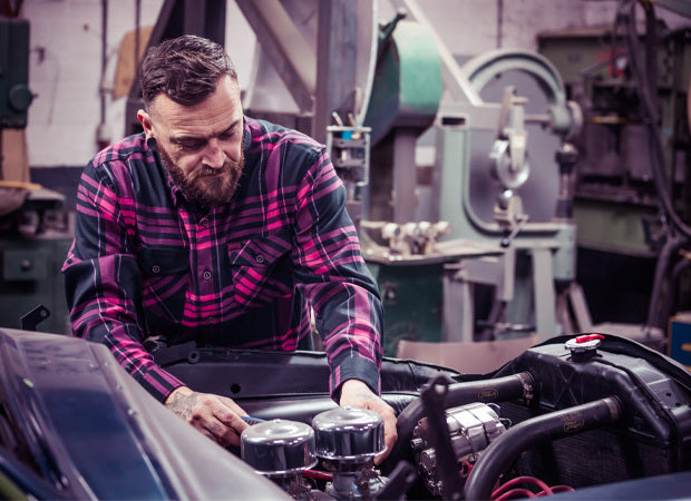 Man wearing a pink and black flannel shirt working on a car engine in a workshop - Lonely Heart Flannel by Greasy Hands Society