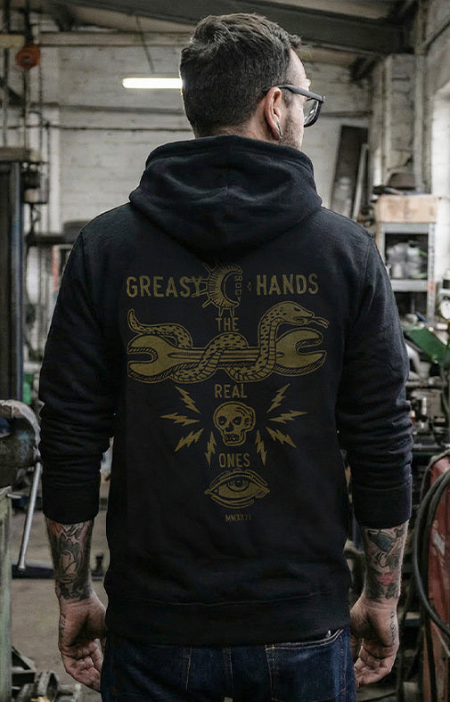 Person wearing a black hoodie with a graphic design on the back in an industrial setting