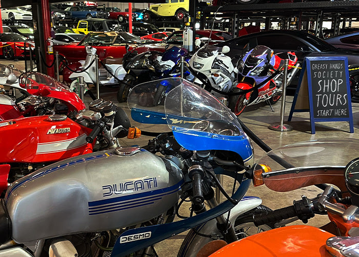 Collection of motorcycles on display in a showroom with a 'Ducati' bike in focus - Greasy Hands Society Shop club location