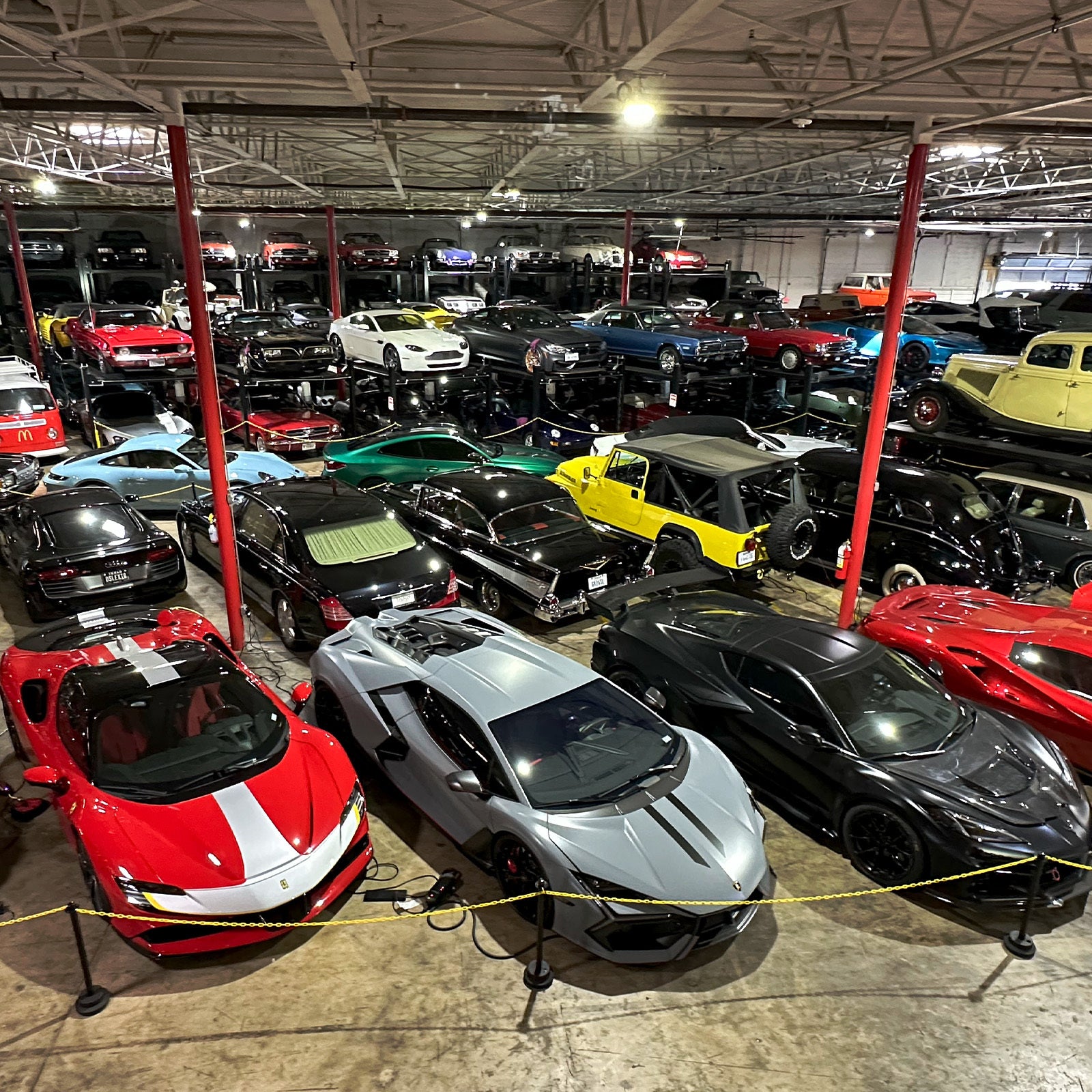 Collection of luxury cars in a showroom with a focus on a white sports car.