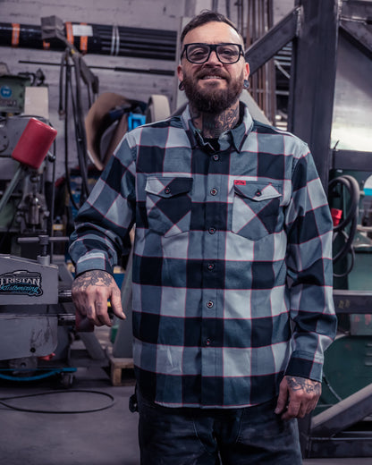 Man wearing a checkered plaid black, white and red flannel shirt standing in a kitchen - The Banger Flannel by Greasy Hands Society